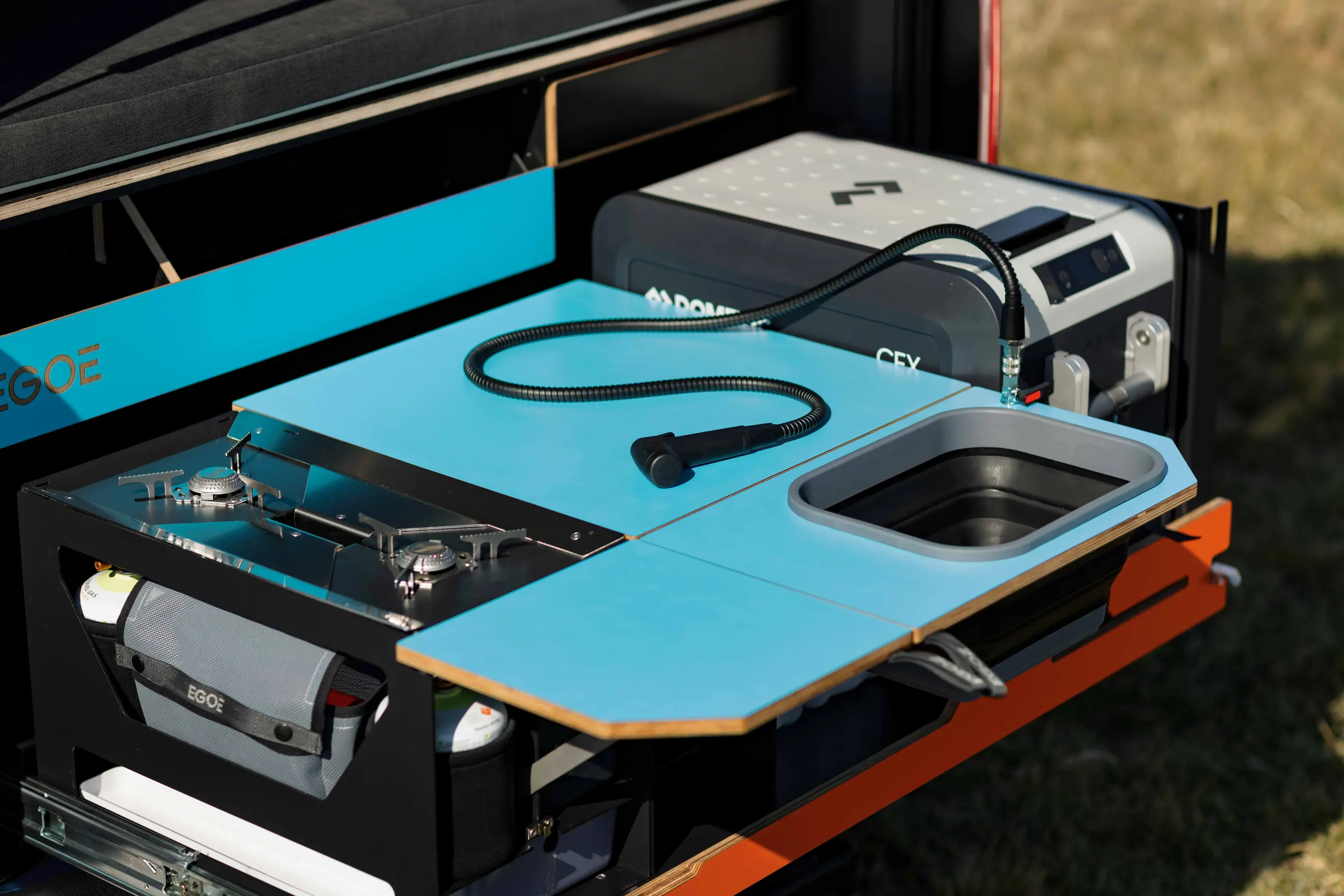 Dva muži vkládají kempingovou vestavbu do vozu.