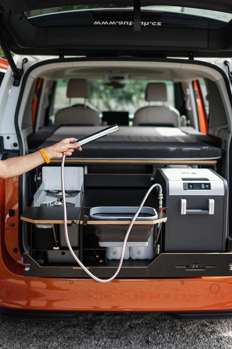 Dva muži vkládají kempingovou vestavbu do vozu.